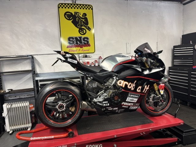 Ducati Panigale on the lift at SNS Motorcycles, under the workshop sign