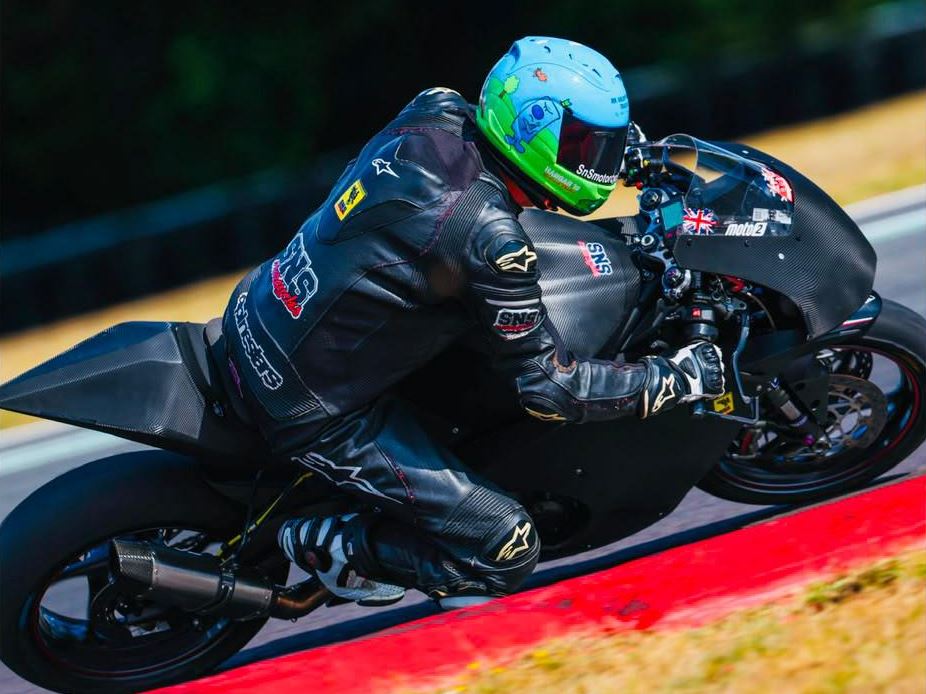 SNS Motorcycles rider cranked over on the Moto2 track bike, knee to the kerb