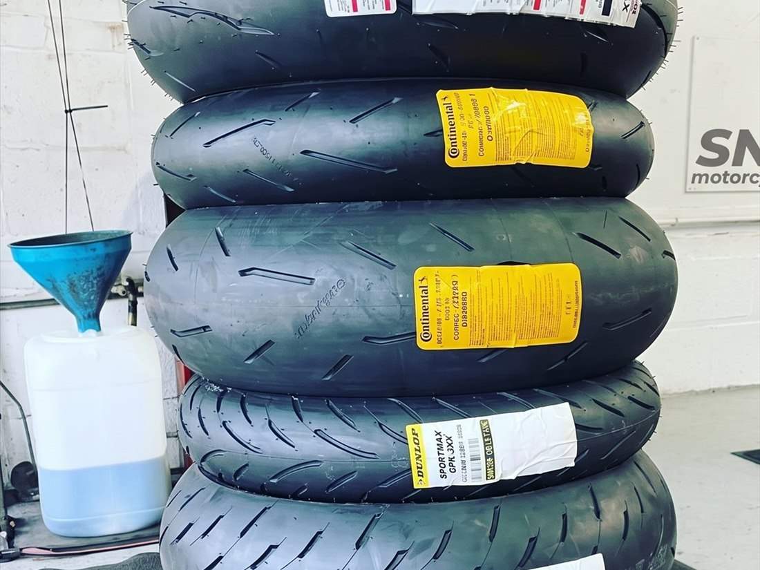 New motorcycle tyres stacked in the SNS Motorcycles workshop